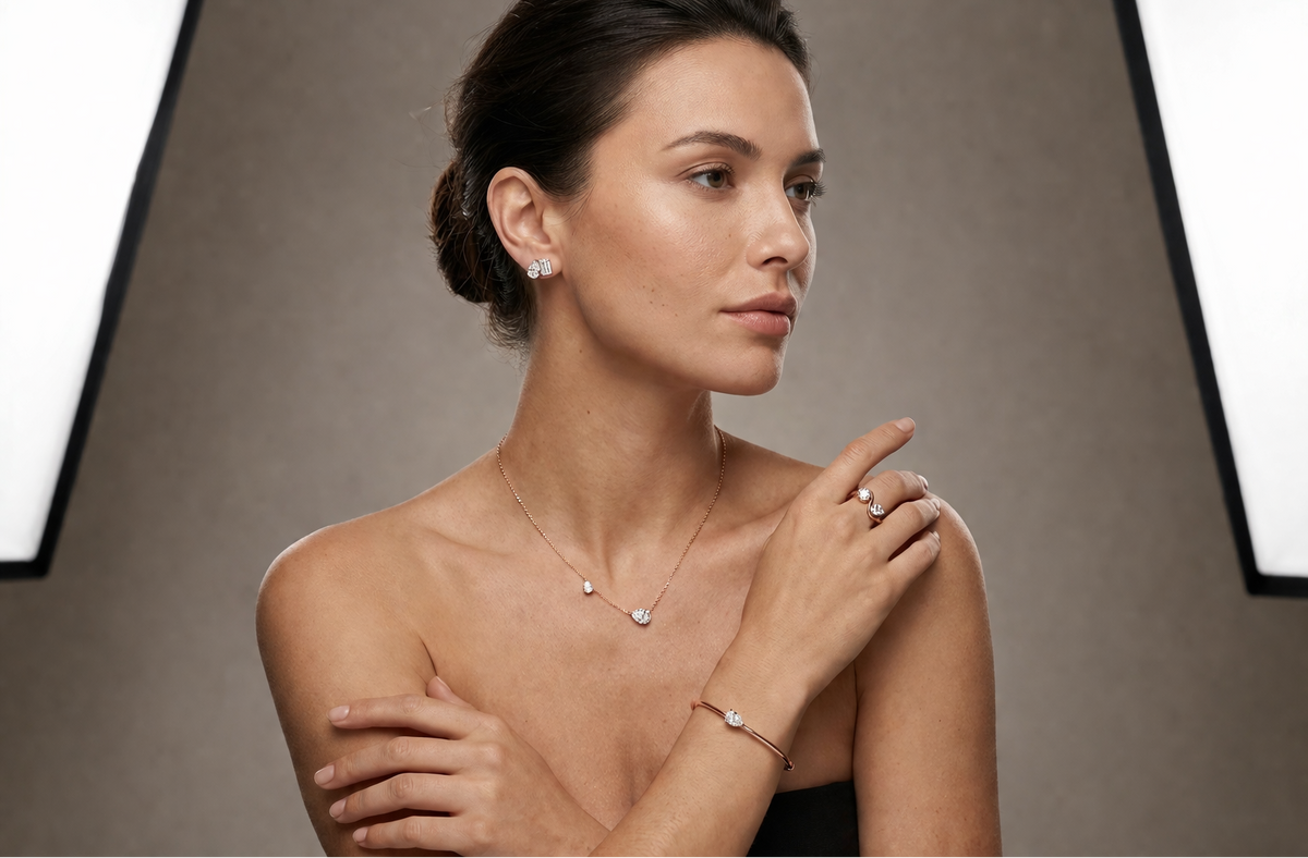 Woman wearing jewelry including a necklace, earrings, and bracelet against a neutral background