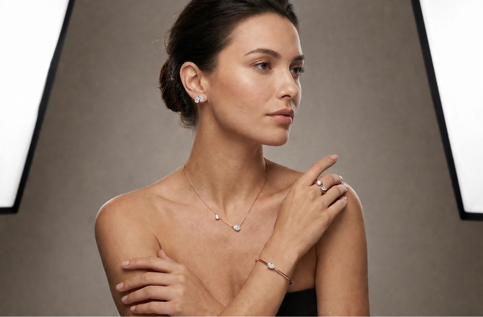 Woman wearing jewelry including a necklace, earrings, and bracelet against a neutral background
