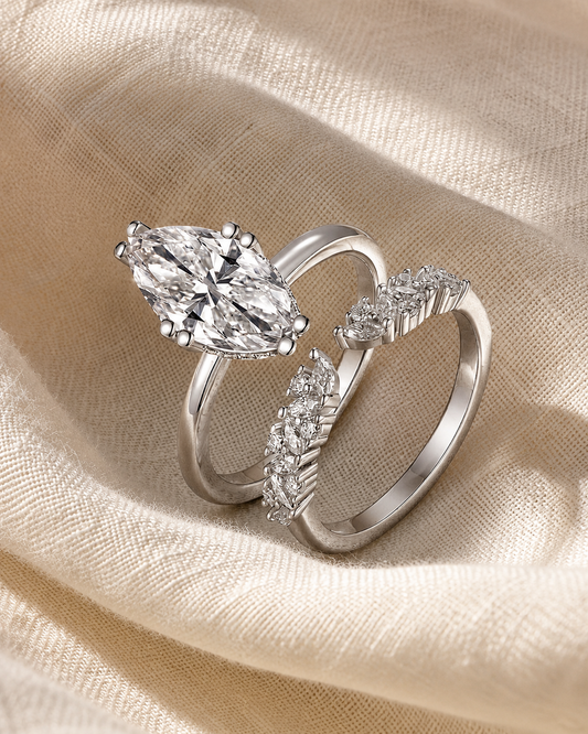 Two-piece silver-tone marquise moissanite ring set angled together on softly draped ivory fabric