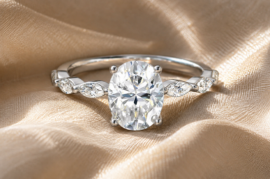 White-gold-plated oval-cut moissanite ring with graduated side stones on champagne fabric