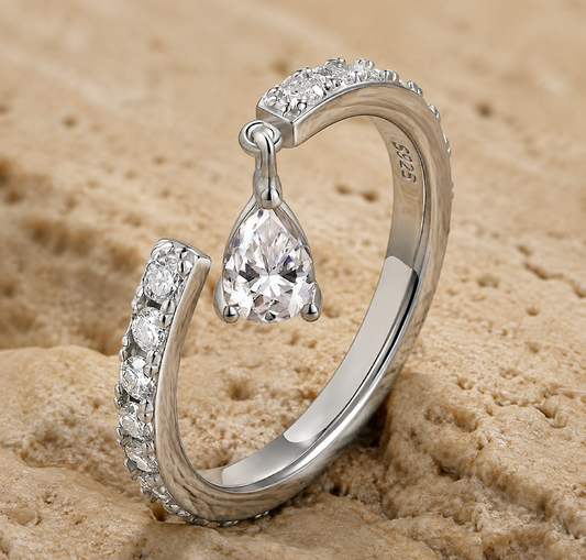 Silver-tone open ring standing upright with a pear-cut moissanite and pavé-set curved end