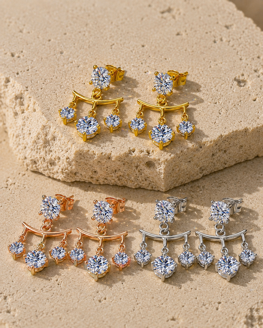 Classic moissanite drop earrings in white, yellow and rose gold-plated finishes on travertine