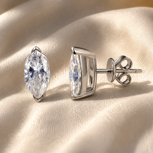 Celeste marquise-cut moissanite stud earrings in front and side profile on champagne fabric