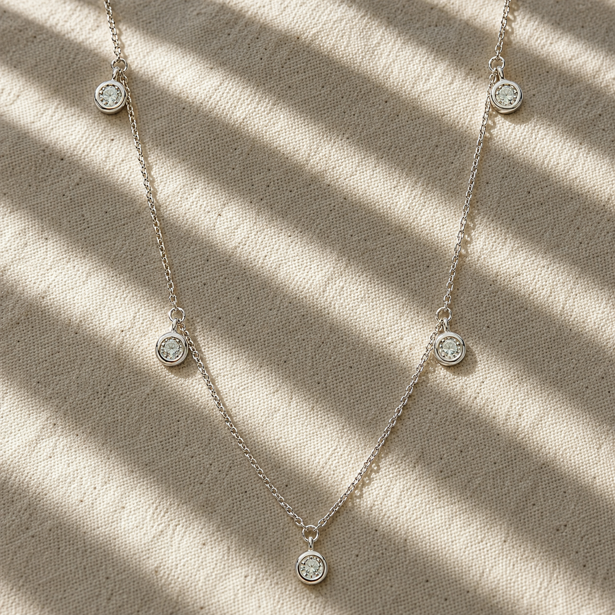 
מבט קדמי על שרשרת כסף 925 עדינה משובצת מואסנייט עם אבנים עגולות בציפוי זהב לבן