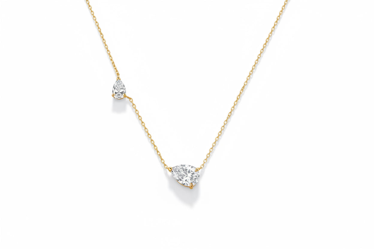 Silver necklace with three teardrop-shaped pendants on a green background